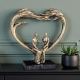 Арт скулптура с бронзов ефект, изобразяваща голямо сърце, образуващо арка над седяща двойка