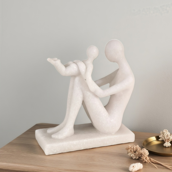 Бяла абстрактна статуетка от полирезин с ефект на камък, изобразяваща седнала майка, която е вдигнала детето си във въздуха в момент на игра