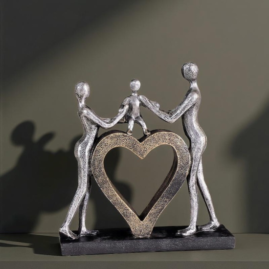 Сребриста статуетка на родители, държащи дете за ръце, стъпило върху златно сърце