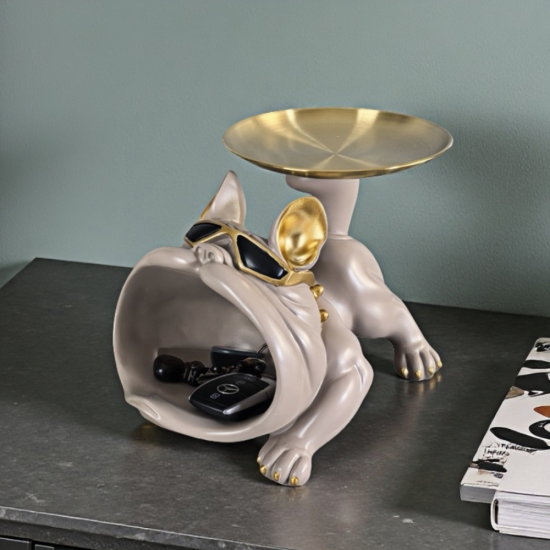 Бежов френски булдог с тъмни очила и широко отворена уста за съхранение на ключове, държащ златен поднос на опашката си