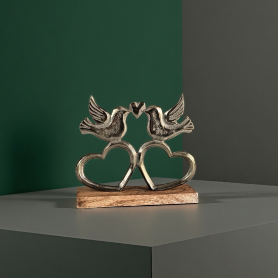 Метална статуетка на два влюбени гълъба, кацнали върху преплетени сърца, разположени на дървена основа